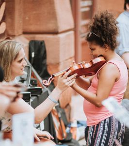 Carolyn Van De Velde helps a girl try a violin at the June 8 "Paint the Town" event at River Music Experience, Davenport.