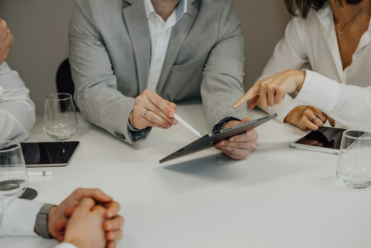a group of people sitting around a table with a pair of scissors
