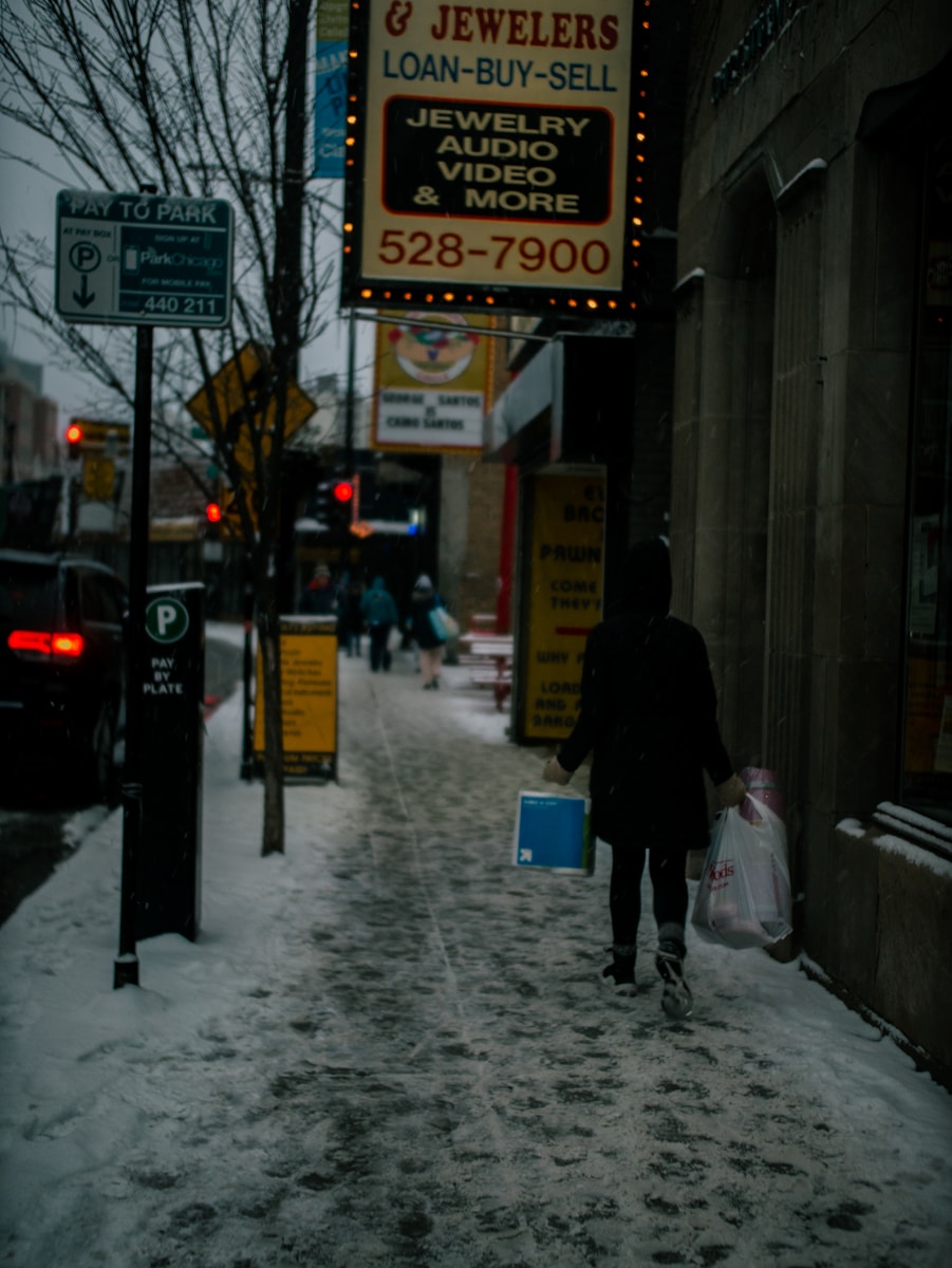 a woman walking down a snow covered sidewalk